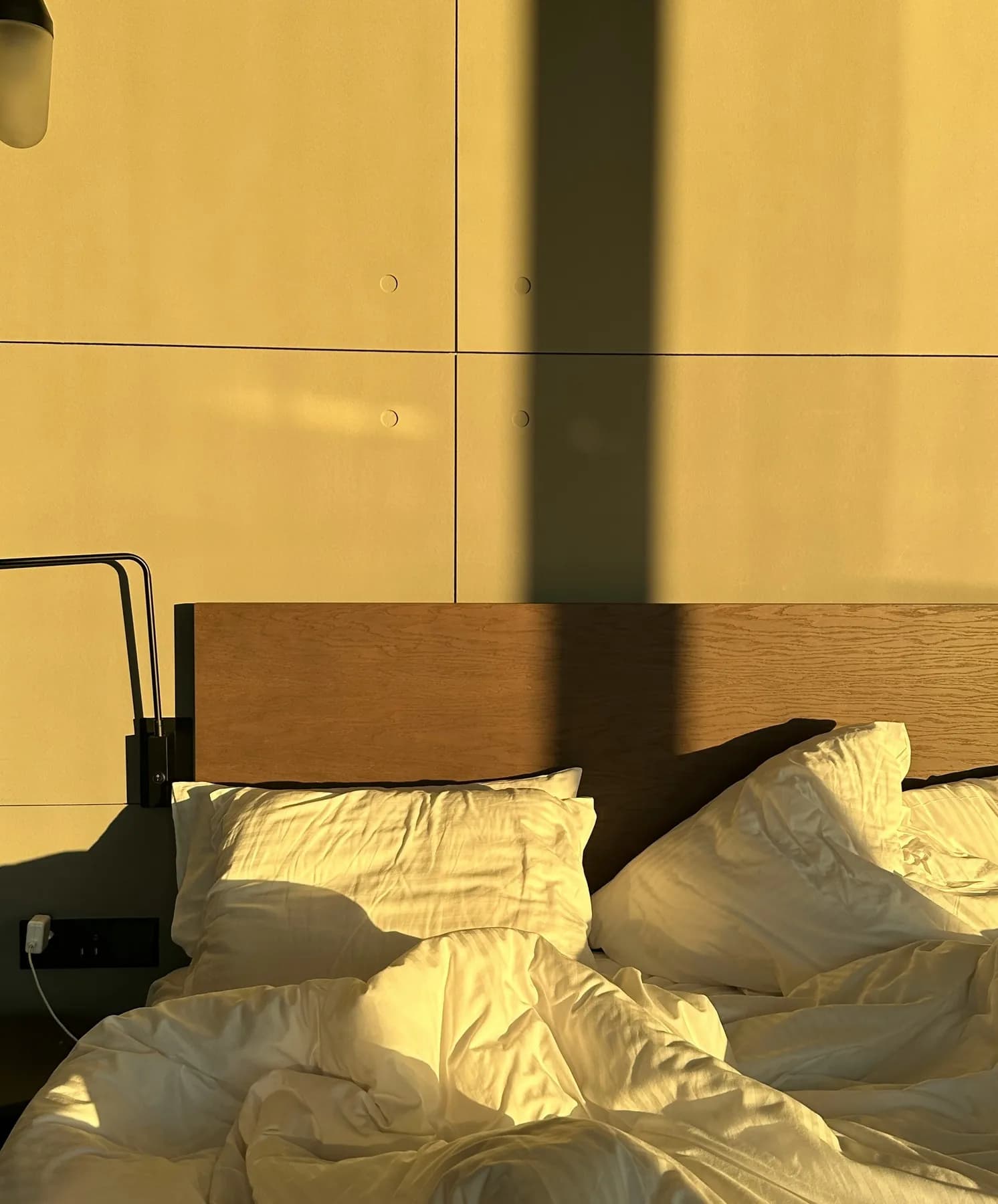 An unmade bed in warm evening light in a keygo apartment